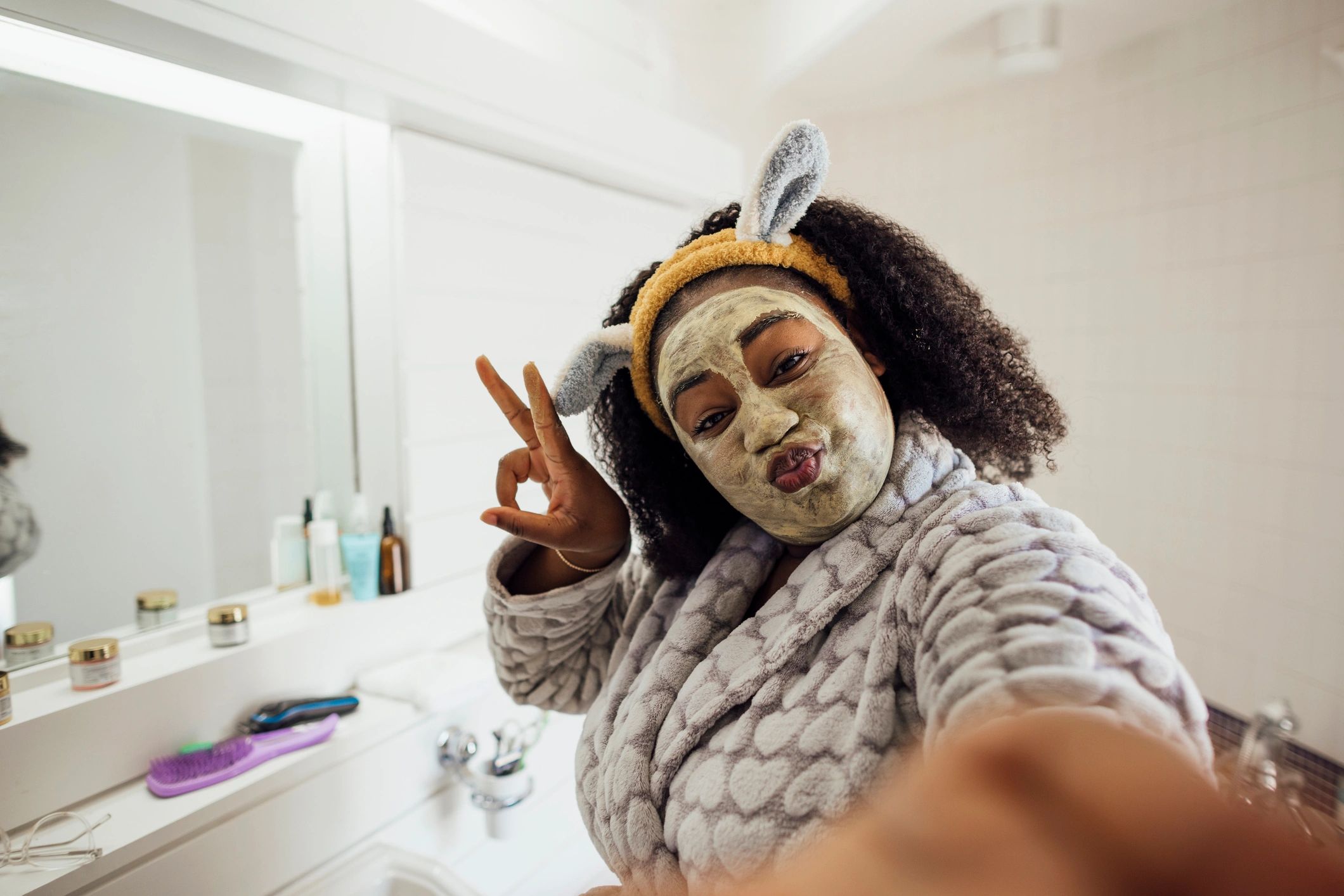 Woman in a bathroom doing an at-home facial mask treatment