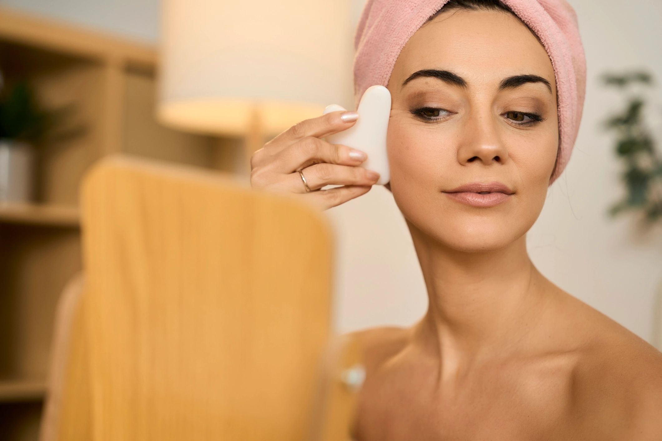 Woman using a gua sha tool during a skincare routine