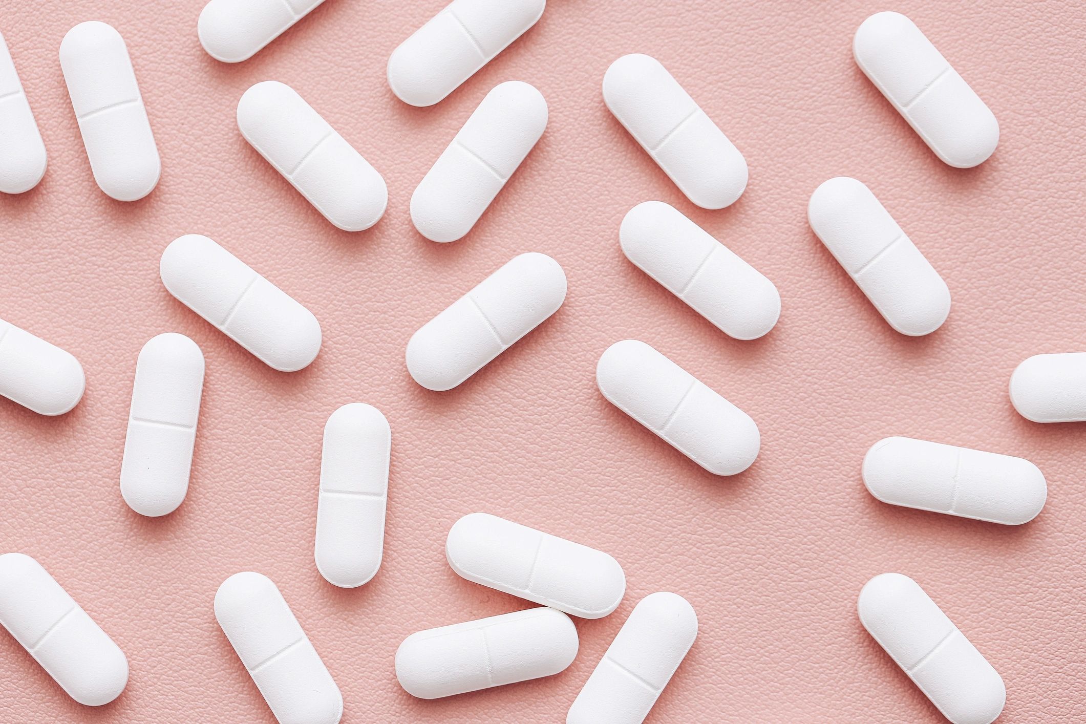 Minimal flat lay of capsules on a pink background