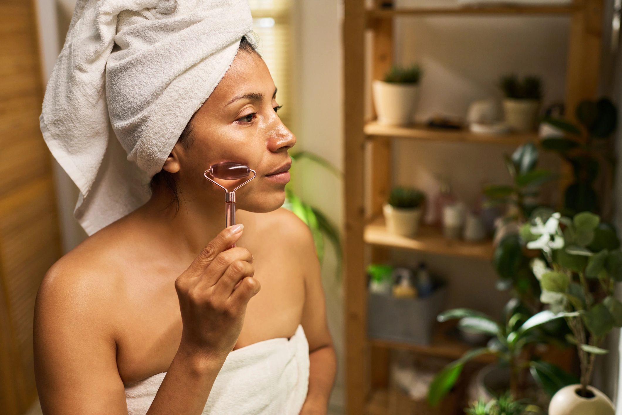 Woman using a facial roller during at-home beauty treatment